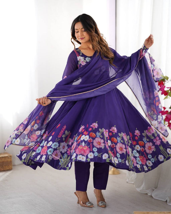 Woman wearing a purple floral dress with a matching dupatta in a bright room.