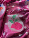 Close-up of a pink fabric with a decorative design featuring a peach and green leaves.