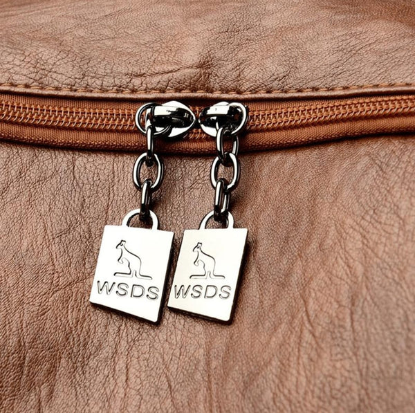Close-up of a brown leather bag with metal zipper and 'WSDS' charms.