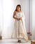 Woman wearing a white floral dress with a matching dupatta in a minimalistic setting.