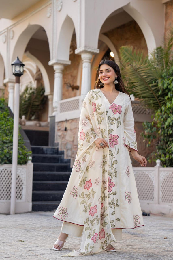Woman in a floral dress standing in front of an architectural building with arches.
