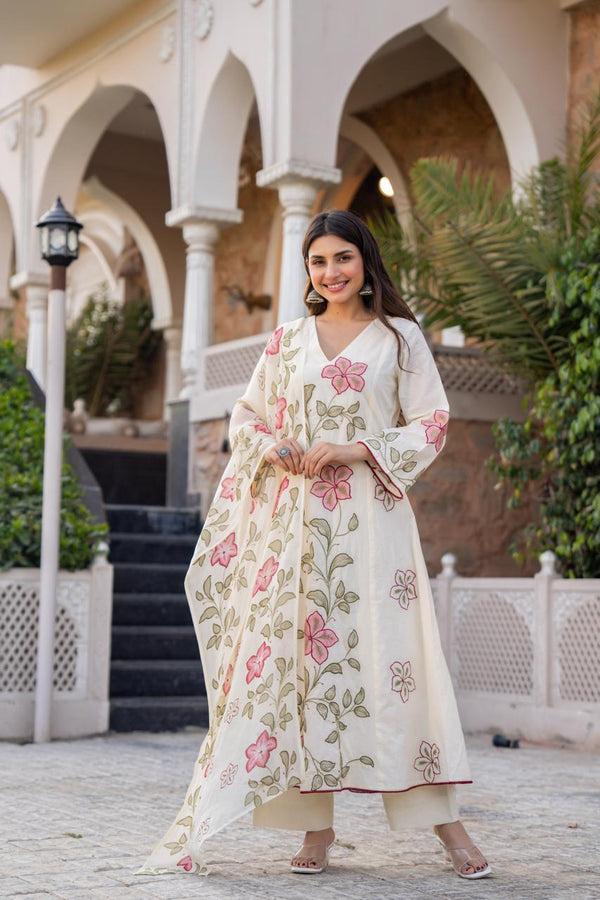 Woman in a floral dress standing in front of an architectural building with arches.