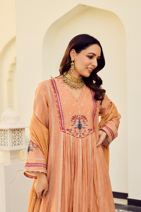 Woman wearing a peach-colored embroidered dress in an architectural setting