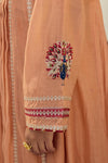 Close-up of peach-colored fabric with peacock embroidery and embellishments.