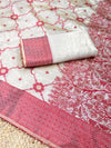White fabric with red floral patterns and a rolled-up white and red fabric on top.