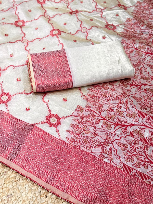 White fabric with red floral patterns and a rolled-up white and red fabric on top.