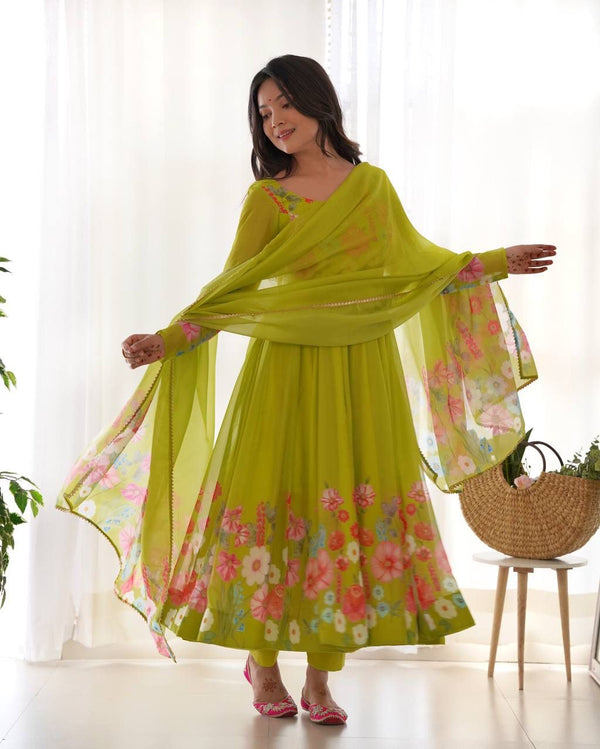 Woman wearing a green floral dress with a matching dupatta in a bright room.