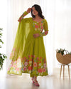 Woman wearing a green floral dress with a sheer dupatta in a bright room.