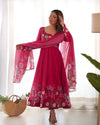 Woman wearing a pink floral dress with a matching dupatta in a bright room.