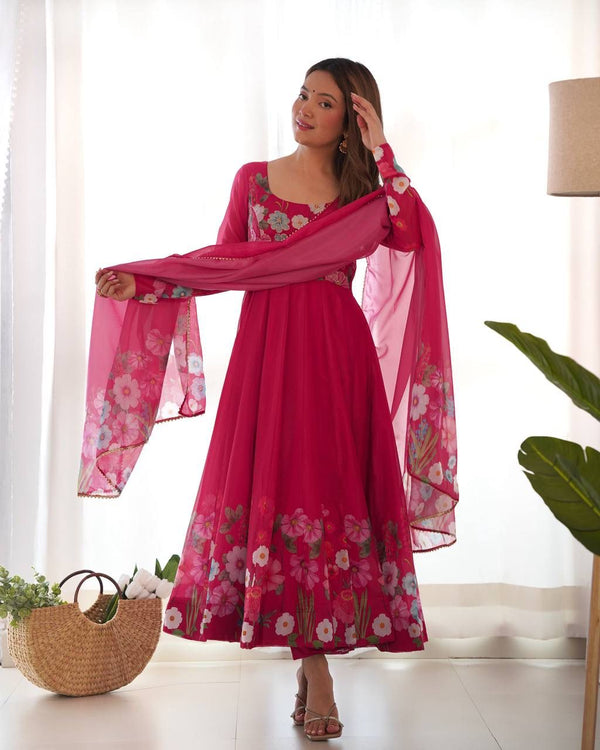 Woman wearing a pink floral dress with a matching dupatta in a bright room.