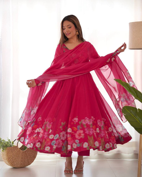 Woman in a bright pink traditional outfit with floral patterns indoors.