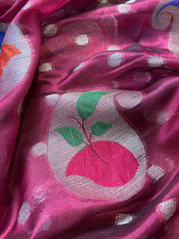 Close-up of a pink fabric with a decorative design featuring a peach and green leaves.