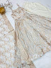 Beige lace dress on a white surface with a small decorative item beside it.