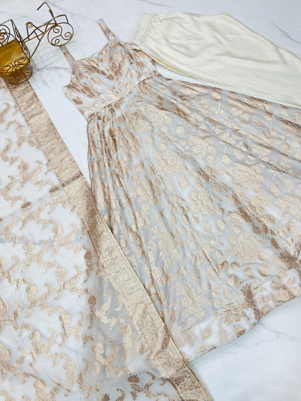 Beige lace dress on a white surface with a small decorative item beside it.