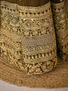 Close-up of intricately embroidered gold fabric on a textured surface