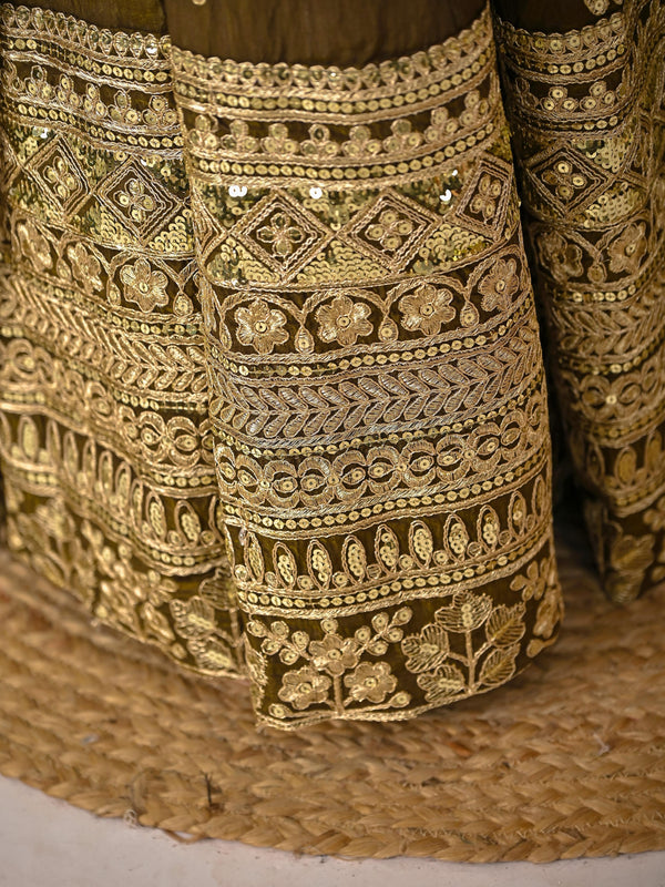 Close-up of intricately embroidered gold fabric on a textured surface