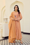 Woman in a gysy suits peach traditional outfit standing in an elegant interior setting.