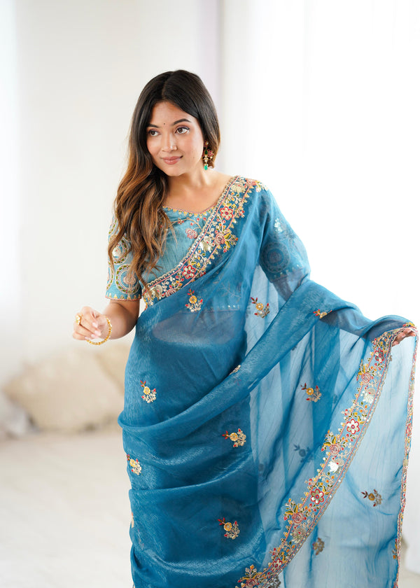 Woman wearing a blue saree with floral embroidery indoors