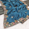 Blue fabric with intricate floral embroidery on a wooden surface