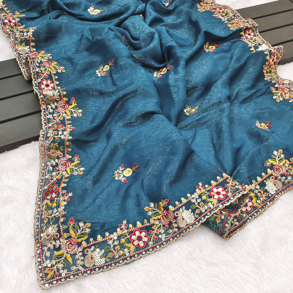Blue fabric with intricate floral embroidery on a wooden surface
