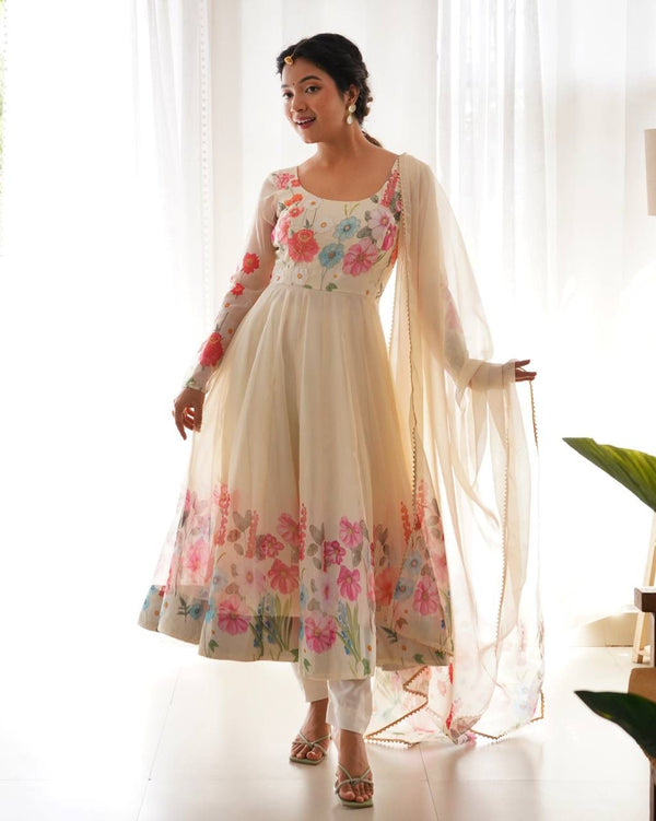 Woman wearing a floral dress with a sheer dupatta against a white curtain background