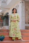 Woman in a light green embroidered outfit standing on steps with a decorative background