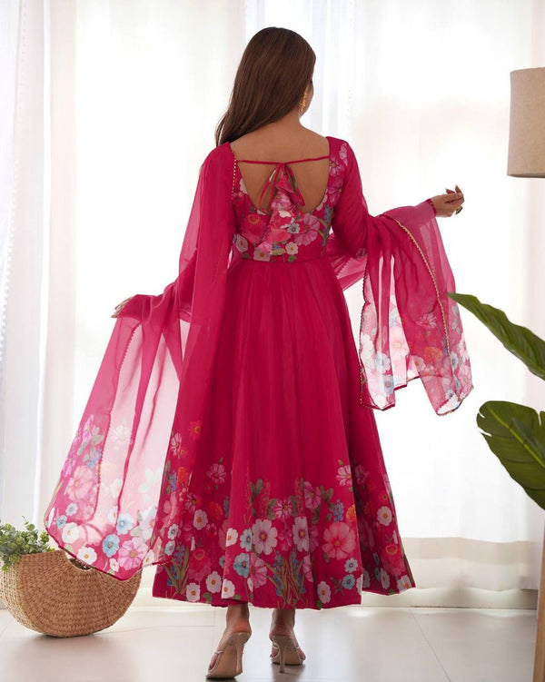 Woman wearing a pink floral dress with sheer sleeves in a bright room.