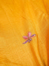 Close-up of a yellow fabric with a small embroidered flower design.