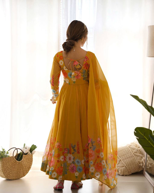 Woman wearing a yellow floral dress standing in a bright room with white curtains.